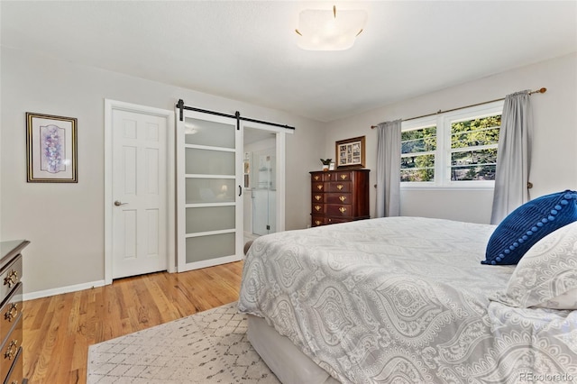 27436 Kennedy Gulch Rd, Conifer, CO 80433 - bedroom with light wood-style floors, a barn door, and connected bathroom