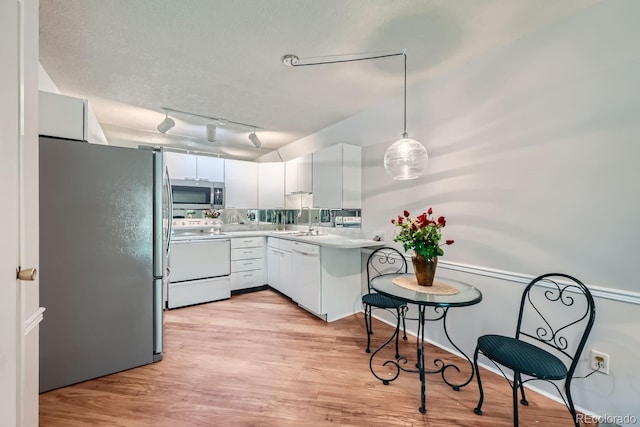 kitchen with hanging light fixtures, sink, white cabinetry, appliances with stainless steel finishes, and light hardwood / wood-style floors