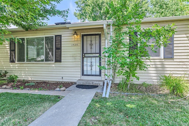 doorway to property with a lawn