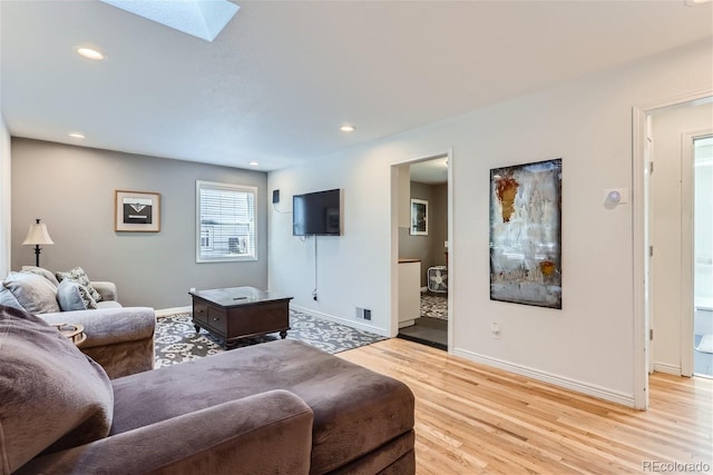 living room featuring light hardwood / wood-style floors and a skylight