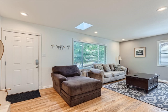 living room with light hardwood / wood-style floors, a skylight, and a wealth of natural light