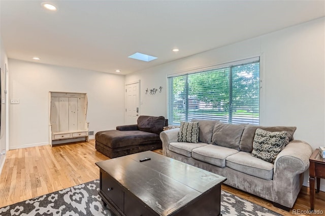 living room with a skylight and light hardwood / wood-style flooring