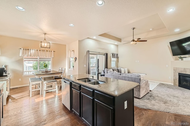 kitchen with a center island with sink, dishwasher, hardwood / wood-style floors, and a tiled fireplace