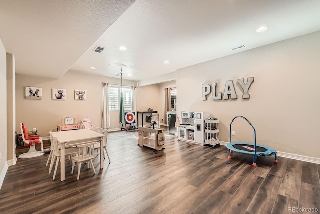 playroom featuring dark wood-type flooring and a textured ceiling