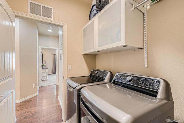 laundry area featuring light hardwood / wood-style flooring, cabinets, and washer and clothes dryer