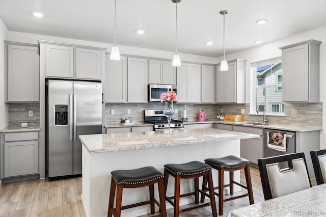10983 Uvalda St, Commerce City, CO 80022 - kitchen with stainless steel appliances, gray cabinetry, decorative backsplash, light wood-style flooring, and recessed lighting