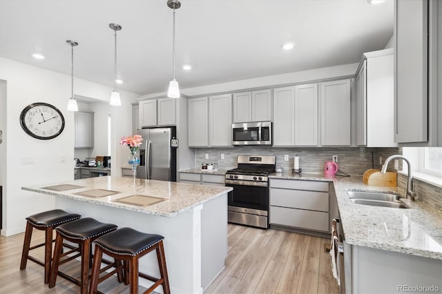 10983 Uvalda St, Commerce City, CO 80022 - kitchen with stainless steel appliances, a sink, gray cabinetry, light wood-style flooring, and tasteful backsplash