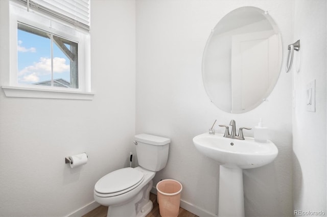 10983 Uvalda St, Commerce City, CO 80022 - half bathroom featuring toilet, baseboards, wood finished floors, and a sink