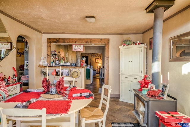 dining space featuring a wood stove, a textured ceiling, and ornamental molding