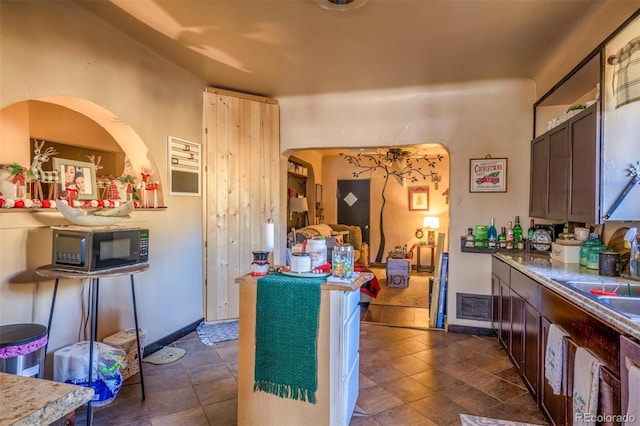 kitchen featuring dark brown cabinetry, dishwasher, and sink