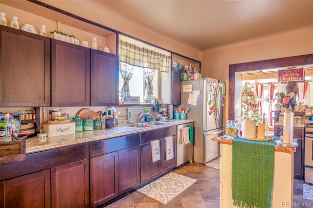 kitchen with light stone countertops, appliances with stainless steel finishes, sink, and a wealth of natural light