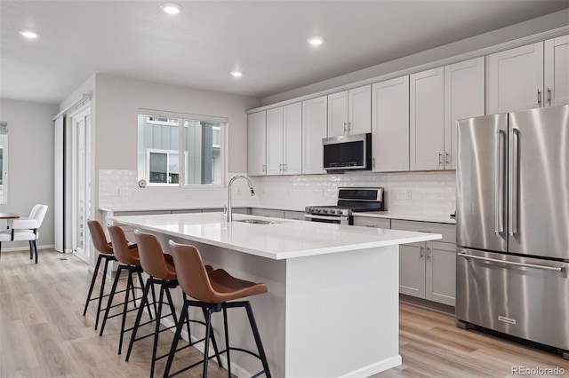 12283 W 57th Ln, Arvada, CO 80002 - kitchen with stainless steel appliances, a center island with sink, light wood-style flooring, recessed lighting, and a breakfast bar area