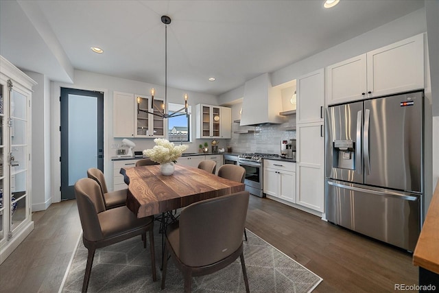 kitchen with pendant lighting, stainless steel appliances, white cabinets, and premium range hood