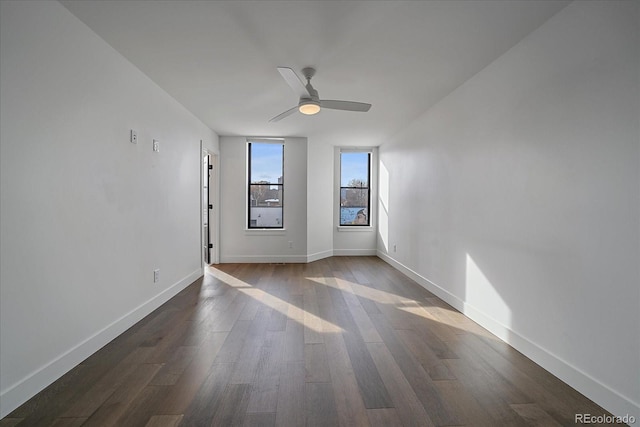 unfurnished room featuring dark wood-style floors, baseboards, and ceiling fan