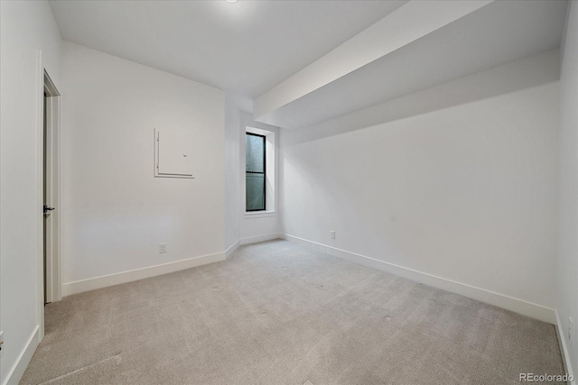 spare room featuring baseboards and light carpet