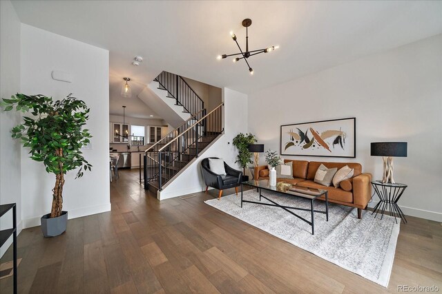 living area featuring stairway, baseboards, an inviting chandelier, and wood finished floors