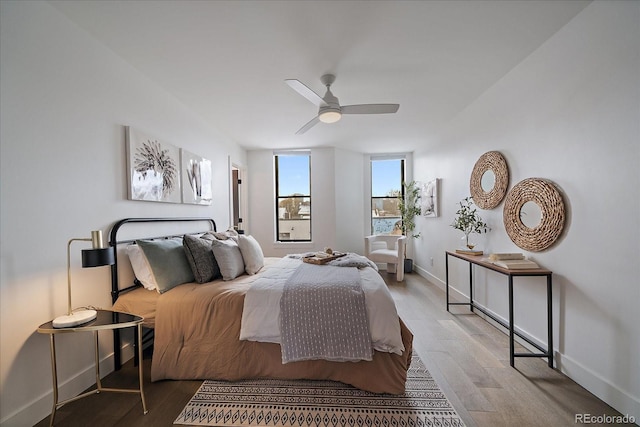 bedroom with light wood-type flooring, baseboards, and a ceiling fan