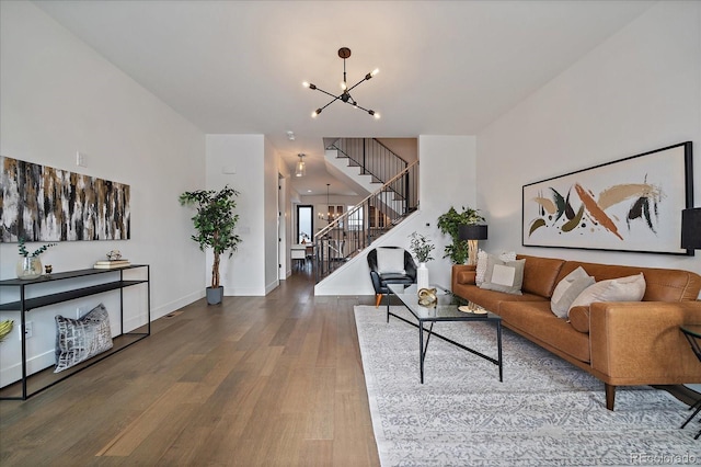 living room with a chandelier, stairs, baseboards, and wood finished floors