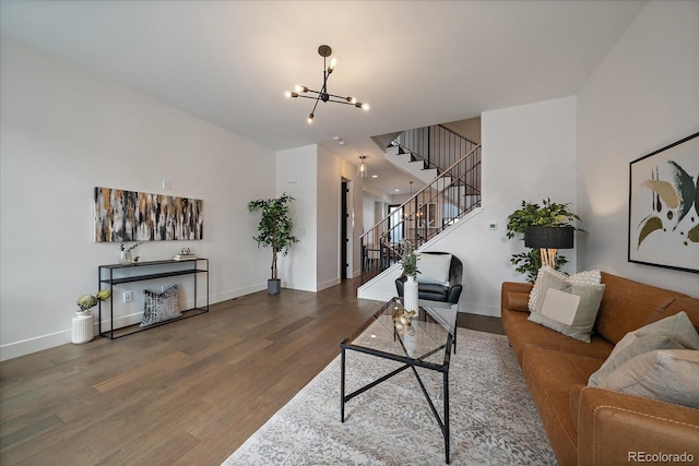 living room featuring stairway, wood finished floors, baseboards, and a chandelier