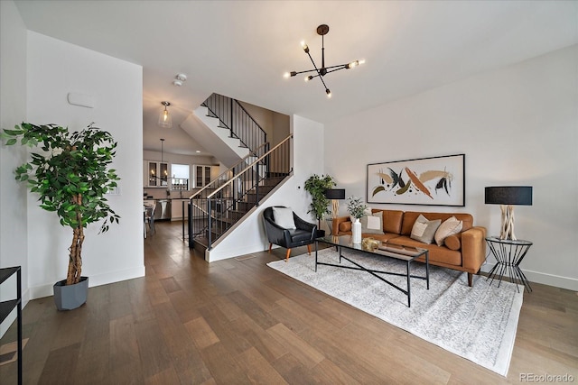 living room with stairs, a notable chandelier, wood finished floors, and baseboards