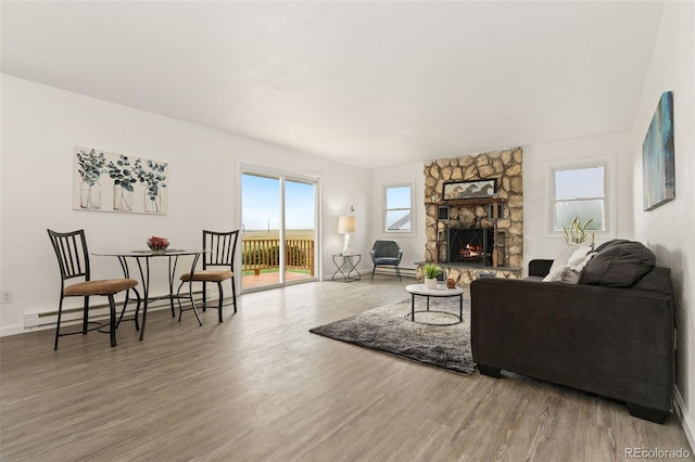 14475 Lanewood St, Brighton, CO 80603 - living room with a baseboard radiator, wood finished floors, and a stone fireplace