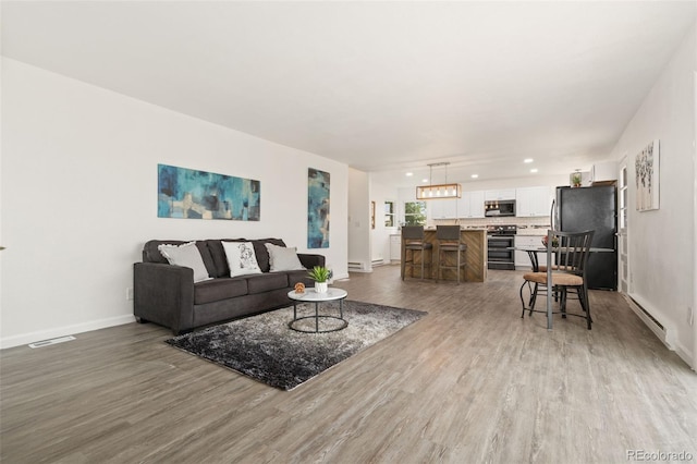 14475 Lanewood St, Brighton, CO 80603 - living area with wood finished floors, a baseboard radiator, and recessed lighting