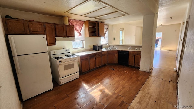 kitchen with white appliances, hardwood / wood-style floors, and sink