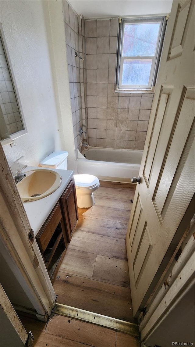 full bathroom with wood-type flooring, vanity, tiled shower / bath combo, and toilet