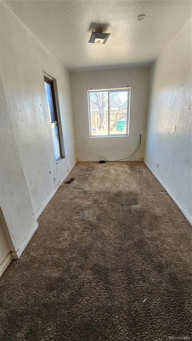 carpeted empty room with a textured ceiling