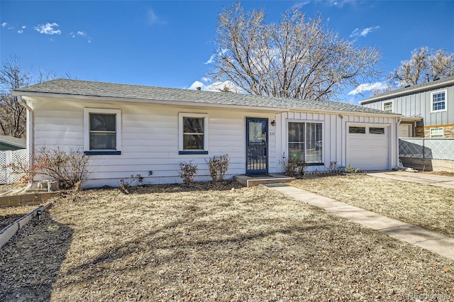 ranch-style home featuring concrete driveway, roof with shingles, an attached garage, fence, and board and batten siding