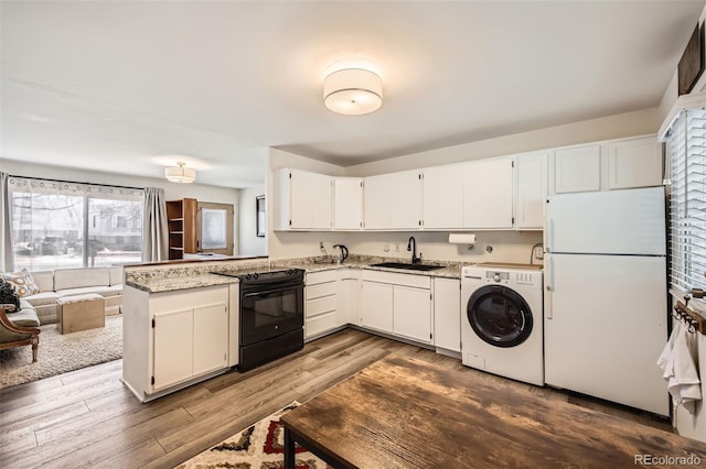 kitchen with electric range, a sink, white cabinetry, freestanding refrigerator, and washer / clothes dryer