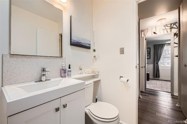 bathroom with tasteful backsplash, baseboards, toilet, wood finished floors, and vanity