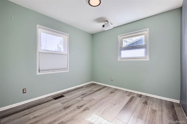 spare room featuring visible vents, baseboards, and wood finished floors