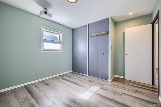 unfurnished bedroom with light wood finished floors, a closet, and baseboards