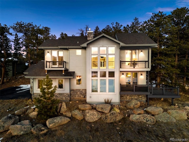 back house at dusk with a balcony