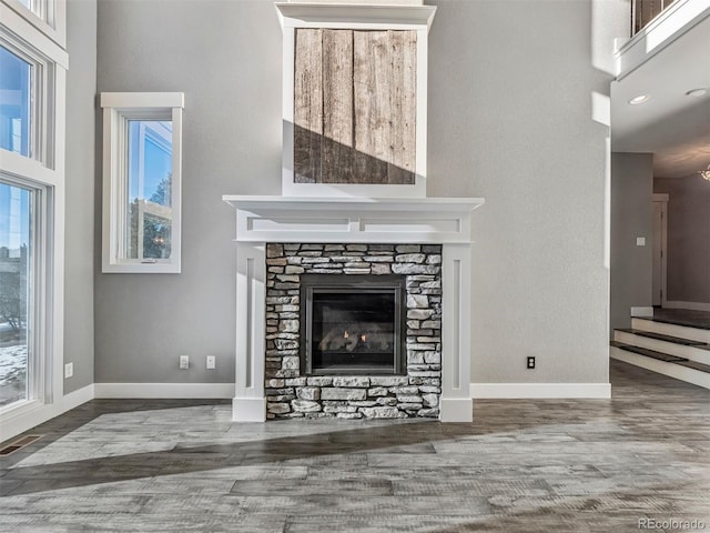 unfurnished living room with a stone fireplace and hardwood / wood-style flooring