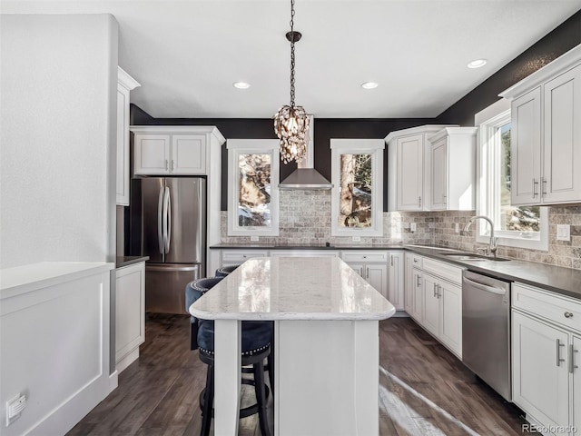 kitchen with dark hardwood / wood-style flooring, stainless steel appliances, sink, a kitchen island, and hanging light fixtures