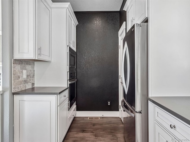 kitchen with backsplash, white cabinetry, dark hardwood / wood-style flooring, and stainless steel appliances