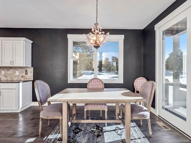 dining area featuring dark hardwood / wood-style flooring, a wealth of natural light, and a chandelier