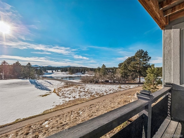 snow covered back of property featuring a water view