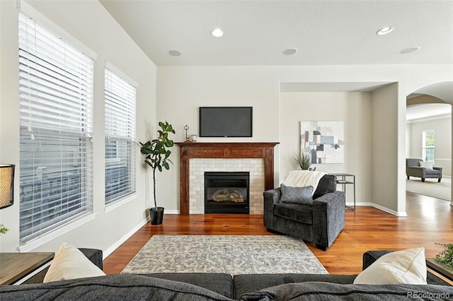 10368 Bluffmont Dr, Lone Tree, CO 80124 - living area with arched walkways, wood finished floors, a brick fireplace, and recessed lighting
