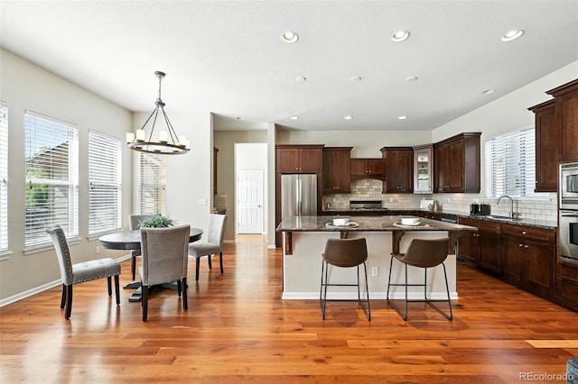 10368 Bluffmont Dr, Lone Tree, CO 80124 - kitchen featuring a chandelier, a kitchen island, a breakfast bar, tasteful backsplash, and recessed lighting