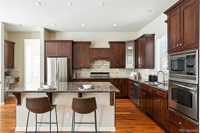 10368 Bluffmont Dr, Lone Tree, CO 80124 - kitchen with appliances with stainless steel finishes, a center island, wood finished floors, tasteful backsplash, and recessed lighting