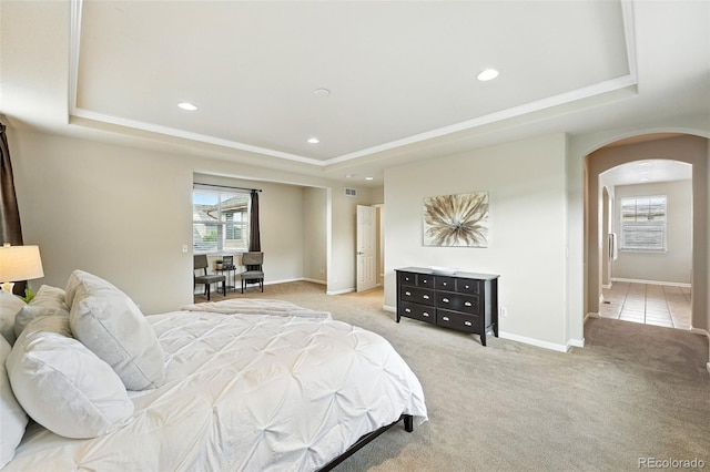 10368 Bluffmont Dr, Lone Tree, CO 80124 - bedroom featuring a raised ceiling, arched walkways, multiple windows, recessed lighting, and light carpet