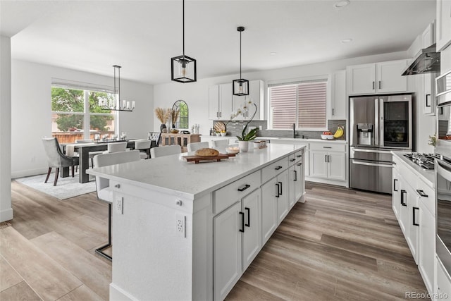 11187 W 53rd Dr, Wheat Ridge, CO 80033 - kitchen with appliances with stainless steel finishes, a kitchen breakfast bar, tasteful backsplash, a kitchen island, and recessed lighting