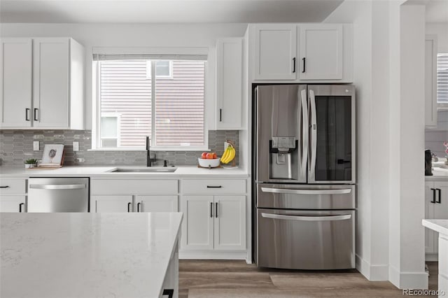 11187 W 53rd Dr, Wheat Ridge, CO 80033 - kitchen featuring stainless steel appliances, white cabinetry, light wood-style floors, and backsplash