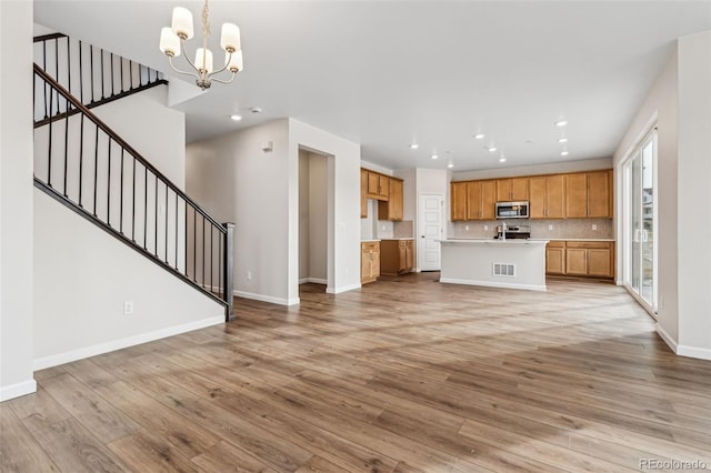 unfurnished living room featuring a chandelier and light hardwood / wood-style floors