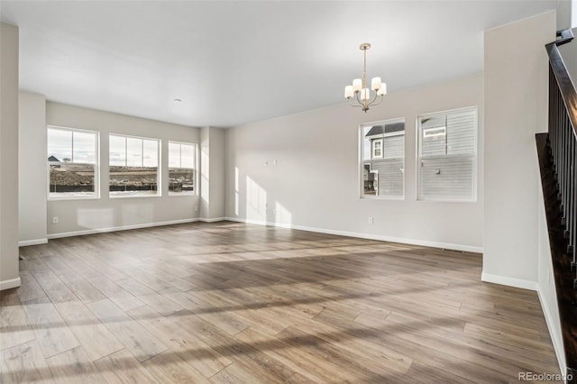 unfurnished living room with a notable chandelier and light hardwood / wood-style floors