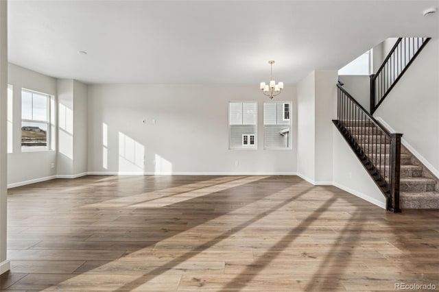 unfurnished living room with an inviting chandelier and hardwood / wood-style floors