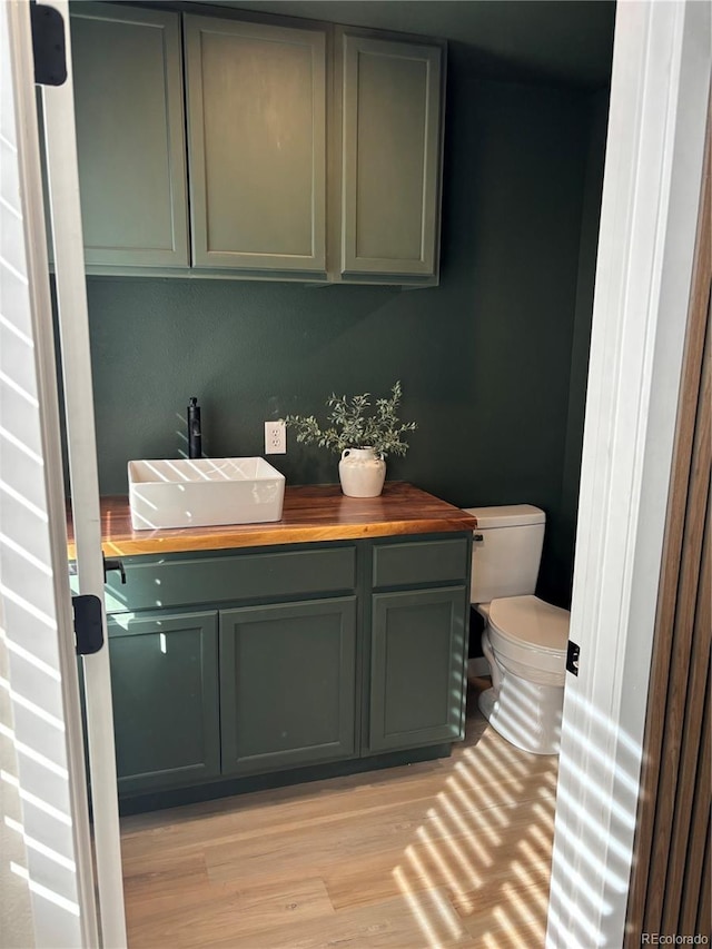 bathroom with wood-type flooring, vanity, and toilet